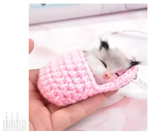 Macro shot of sleeping plush cat in pink hand-crocheted sleeping bag with key ring detail