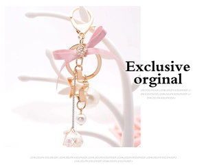Detail of pink bow keychain with pearl charms and gold star on jewelry stand