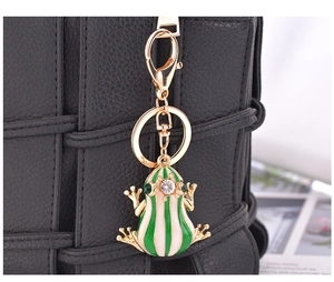 Porte-clés grenouille rayé vert avec cristal sur un sac à main en cuir noir