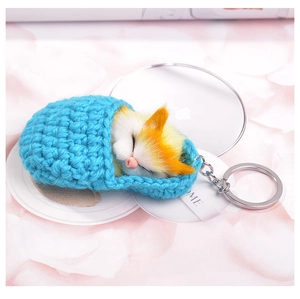 Detailed macro view of orange tabby cat plush in blue knit bag with silver keychain