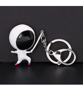 Close-up of a white astronaut keychain with metallic ring and lobster clasp on black background