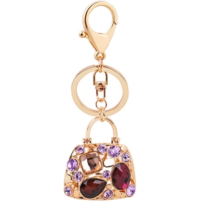 Luxury gold handbag keychain with purple and amber rhinestones on a white background