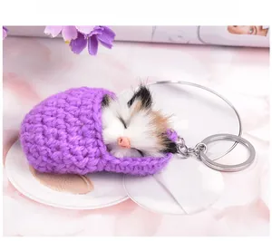 Close-up of a purple knitted sleeping bag keychain with a realistic calico cat plush