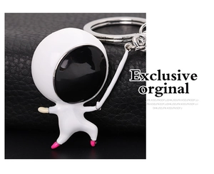 Close-up of a white enamel astronaut keychain with pink accents on black leather