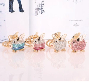 Detail view of crystal rhinestone pig keychains in blue, rose, white, and pink