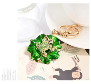 Close-up of golden frog keychain on green lotus leaf with sparkling green rhinestones