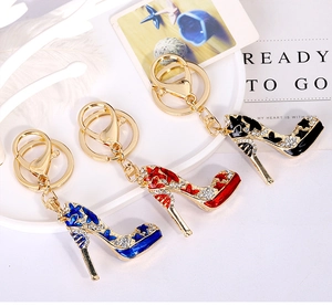 Detailed macro of rhinestone-studded high heel keychains in blue, red, and black enamel