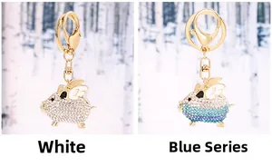 Detailed comparison of white and blue rhinestone flying pig alloy keychains with gold wings
