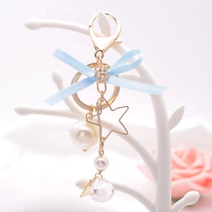 Elegant Korean style bow keychain with blue ribbon, pearls and gold star on a white stand
