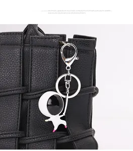 Detail shot of a white astronaut keychain with metallic ring on a black leather bag