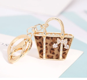 Detail of leopard print handbag keychain featuring a gold frame and rhinestone bow ornament