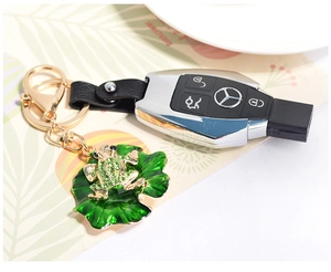 Detail of enameled green frog keychain with rhinestones and black leather strap