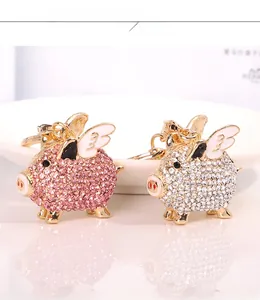Close-up of pink and silver flying pig keychains with sparkling rhinestones and gold plating
