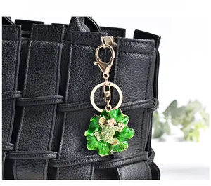Close-up of green enamel lotus leaf and golden frog keychain with sparkling rhinestones