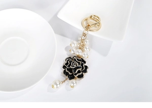 Détails du porte-clés camélia noir avec perles blanches et accents de diamants fins