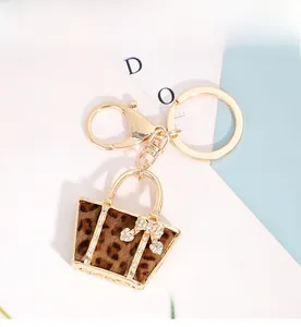 Macro detail of tote bag keychain with leopard print fur and rhinestone bow charm