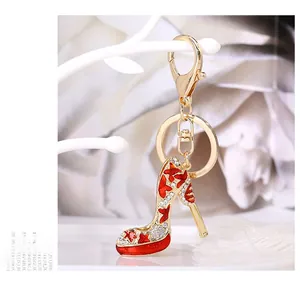 Detailed close-up of a luxury red high heel keychain with rhinestones on a white stand