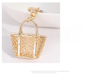 Detailed view of a gold-plated miniature handbag keychain with intricate hollow patterns