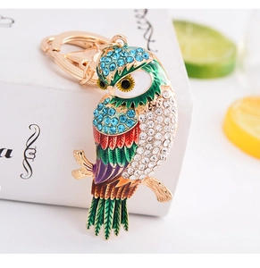 Détail du porte-clés hibou avec strass bleus et plumes en émail coloré sur branche dorée