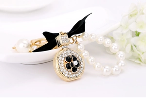 Detail of perfume bottle charm with black camellia, pavé rhinestones and pearl chain