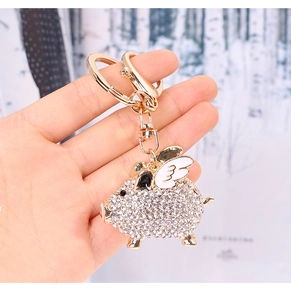 Close-up of flying pig keychain featuring white rhinestones and gold alloy wings