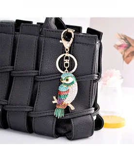 Détail du porte-clés hibou en émail coloré avec strass sur un sac à main noir élégant