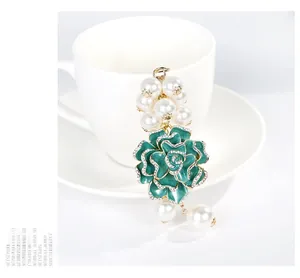 Détail d'un pendentif camélia en émail vert de luxe avec strass et perles blanches