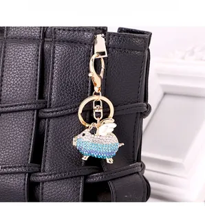 Detailed close-up of a flying pig keychain with blue crystals on a black leather bag