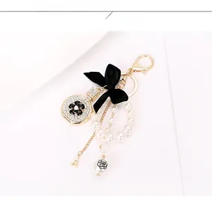 Detailed view of perfume bottle keychain with black bow, pearls and Eiffel Tower charm