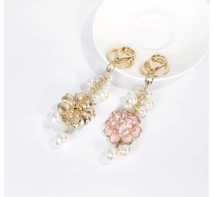 Détail de pendentifs camélia avec émail rose, strass et perles artificielles fines