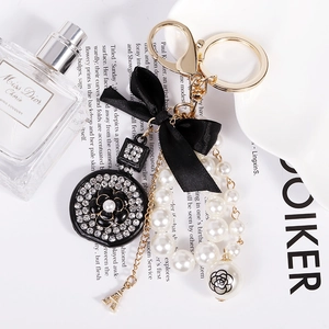 Detail of luxury alloy keychain with black bow, white pearls, and camellia pendant