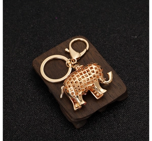 Detail of gold elephant keychain with pink rhinestones and hollow floral patterns