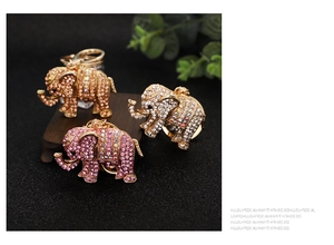 Detailed close-up of elephant keychains with pink, gold, and silver rhinestones on wood