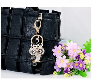 Dettaglio di un ciondolo a forma di gufo dorato con smalto nero su una borsa