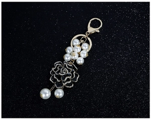 Détail du porte-clés fleur en émail noir avec cristaux étincelants et perles blanches