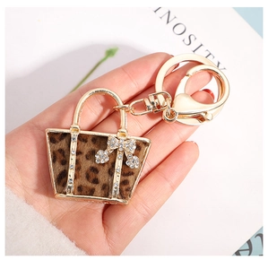 Close-up of leopard print handbag keychain with rhinestone bow held by a model