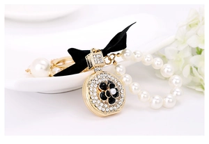 Detailed close-up of a golden camellia charm with white rhinestones and pearl chain