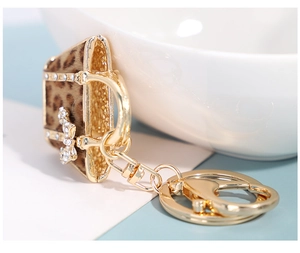 Macro detail of leopard print handbag keychain with gold hardware and rhinestone bow
