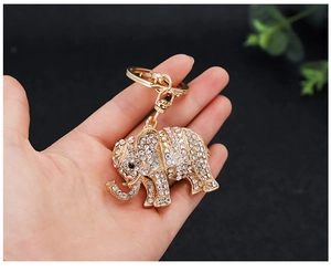 Macro shot of gold elephant keychain with white rhinestones held by a hand