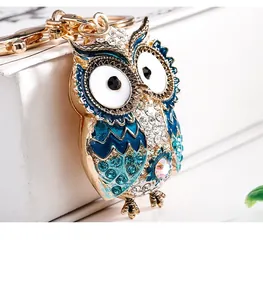 Close-up of golden owl keychain with blue enamel inlay and sparkling rhinestones