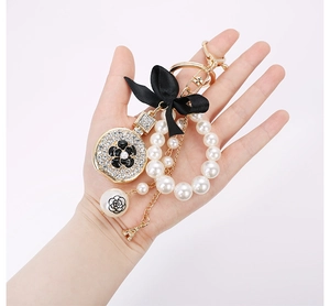 Detail of luxury keychain with black camellia, satin bow, pearls and Eiffel Tower charm