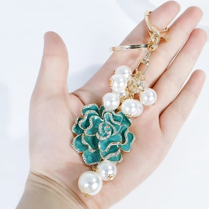 Porte-clés camélia en émail vert avec perles et strass sur crochet en métal doré