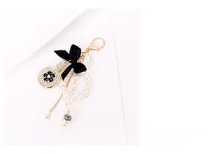 Close-up of elegant perfume bottle charm with camellia flower and black ribbon bow