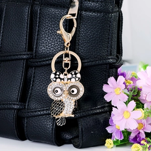 Portachiavi a forma di gufo con strass e fiocco su borsa in pelle intrecciata nera