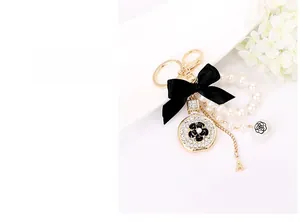 Detail of gold alloy keychain featuring black bow, camellia charm, and Eiffel Tower