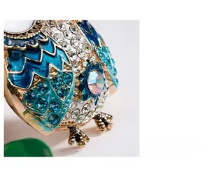 Macro detail of alloy owl keychain with blue enamel wings and sparkling rhinestones