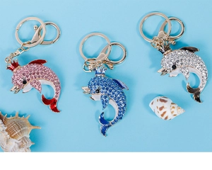 Detailed close-up of crown dolphin keychains in pink, blue, and silver with rhinestones