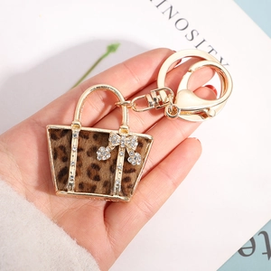 Creative leopard print handbag keychain with golden alloy finish and crystal bow detail