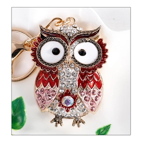 Close-up of owl keychain with red enamel and sparkling rhinestones on gold alloy base
