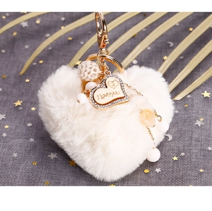 Détail d'un porte-clés cœur en peluche avec fermoir doré et pendentif cœur gravé